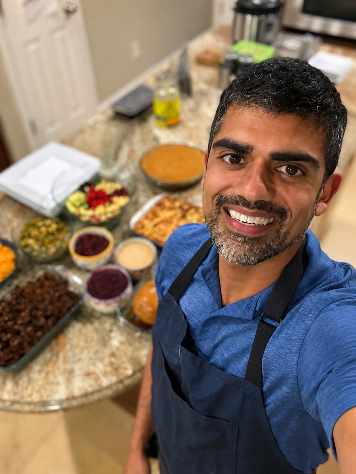 Dr. Rak smiling beside a full spread of plant-based dishes from a Mindful Meals cook-along